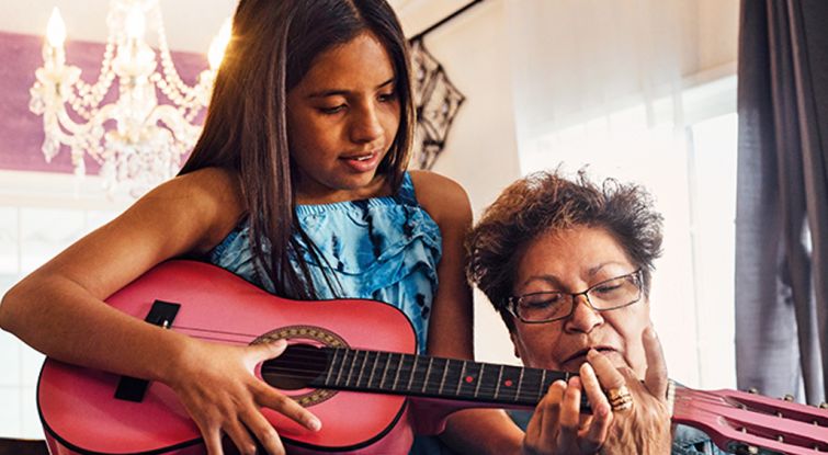 Girl playing the charango to her grandma